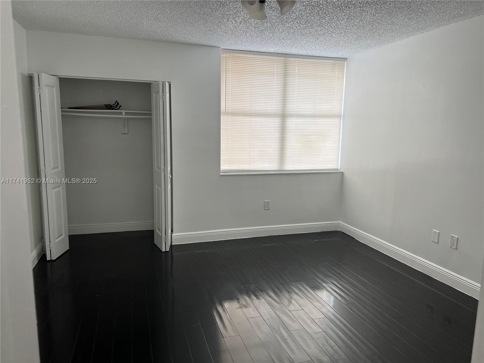 4372 West 11th Lane, Unit 30 Hialeah, FL 33012 - Photo 15 of 23 an empty room with wooden floor and windows