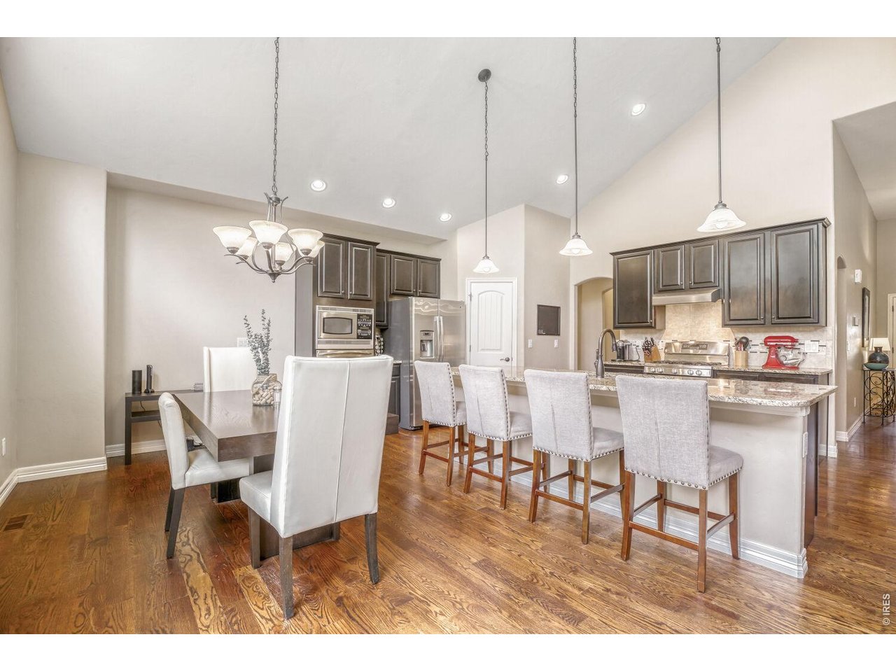 7992 St Street Frederick, CO 80530 - Photo 4 of 28 a dining room kitchen with stainless steel appliances kitchen island granite countertop a table chairs and a refrigerator