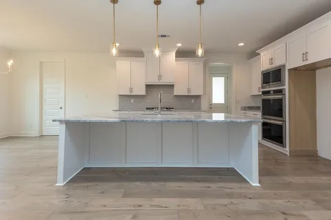 a large kitchen with kitchen island a stove a refrigerator a sink a center island and a wooden floor