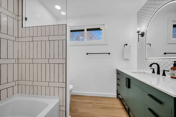 a bathroom with a tub sink and mirror