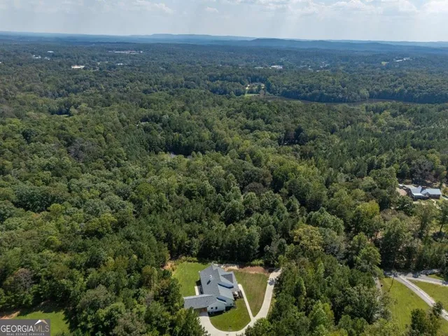 an aerial view of residential house with outdoor space and trees all around