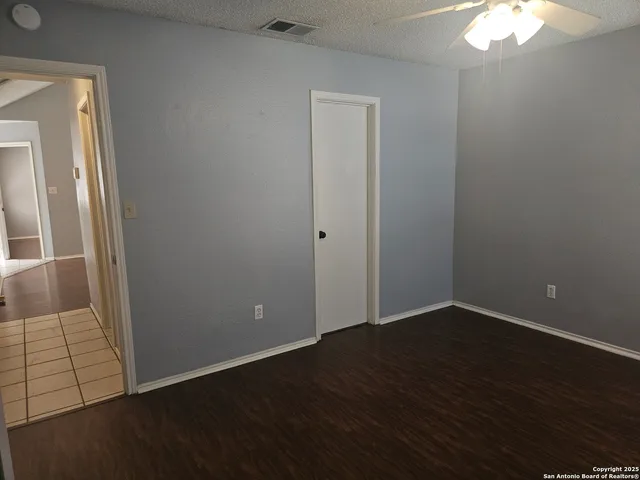 an empty room with wooden floor and chandelier fan