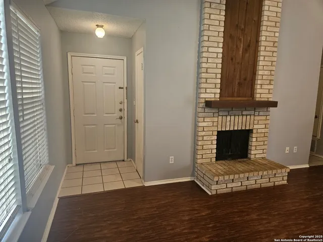 an empty room with wooden floor fireplace and windows