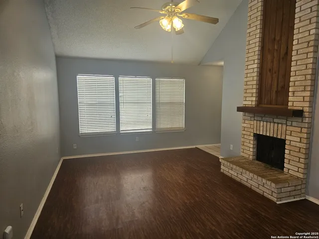 an empty room with wooden floor a fireplace and windows