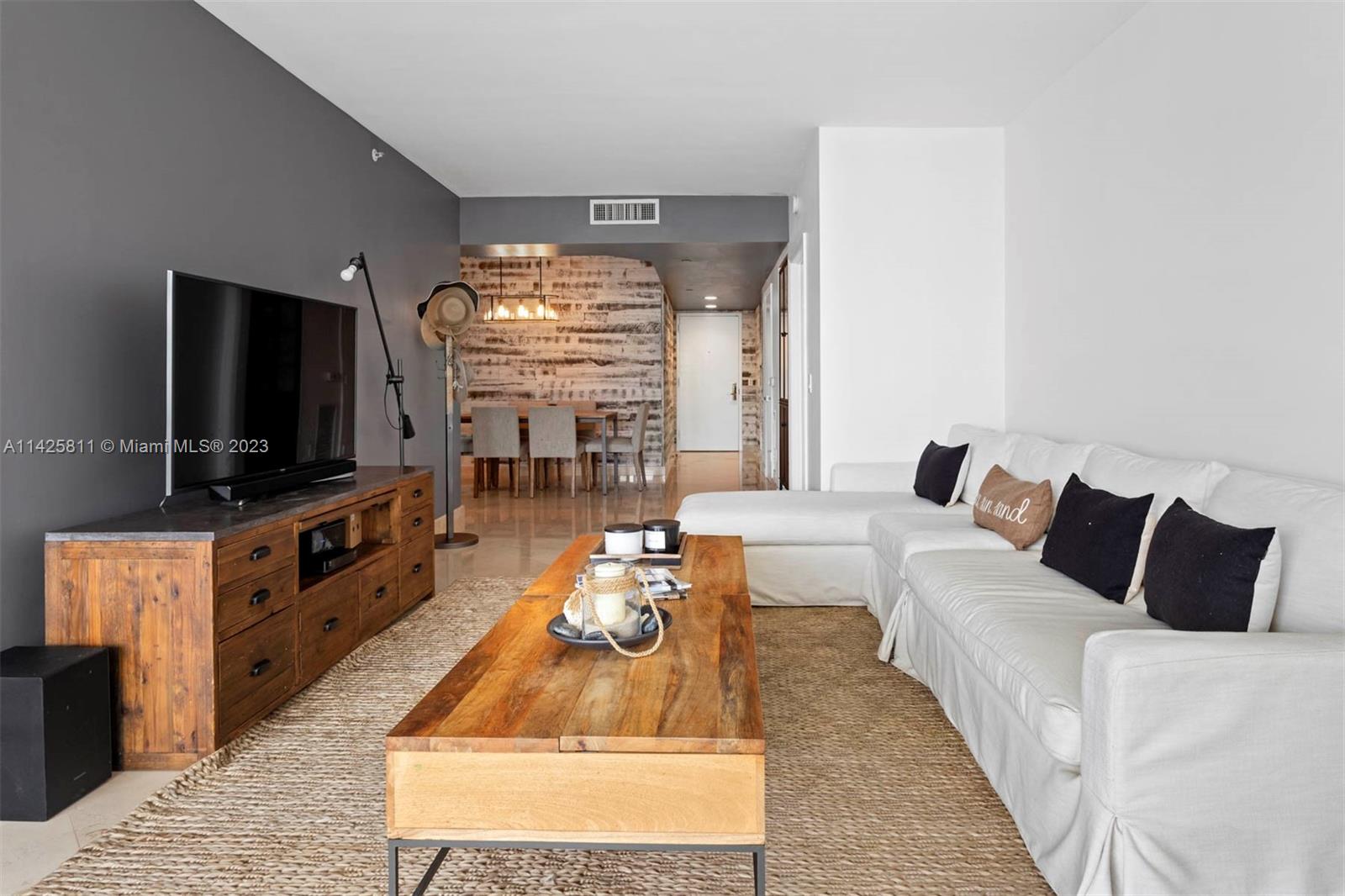 4779 Collins Avenue, Unit 1908 Miami Beach, FL 33140 - Photo 2 of 36 a living room with furniture and a flat screen tv