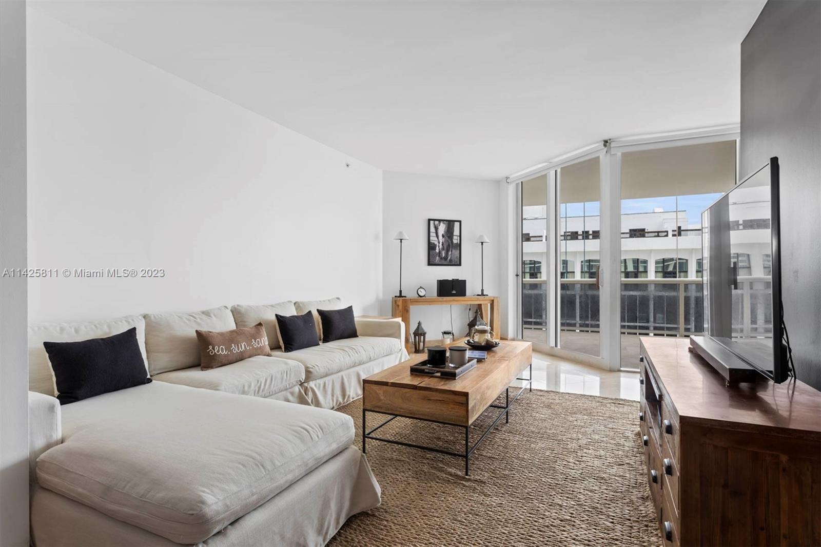 4779 Collins Avenue, Unit 1908 Miami Beach, FL 33140 - Photo 3 of 36 a living room with furniture a rug and a flat screen tv