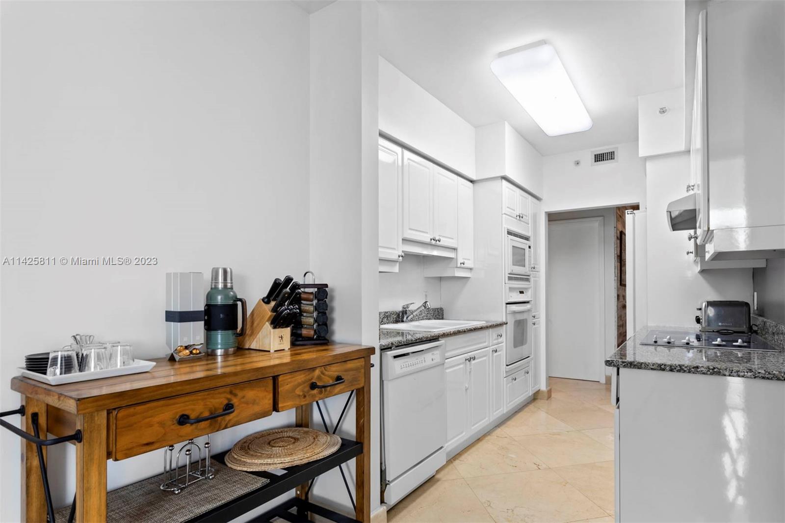 4779 Collins Avenue, Unit 1908 Miami Beach, FL 33140 - Photo 7 of 36 a kitchen with a sink appliances and cabinets