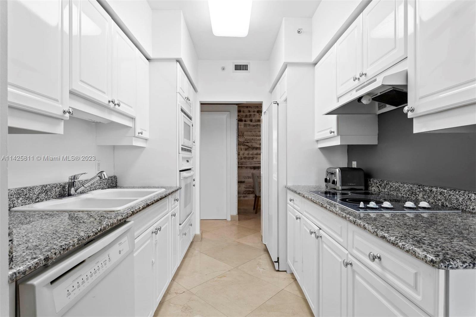4779 Collins Avenue, Unit 1908 Miami Beach, FL 33140 - Photo 9 of 36 a kitchen with granite countertop kitchen island a sink stainless steel appliances and cabinets
