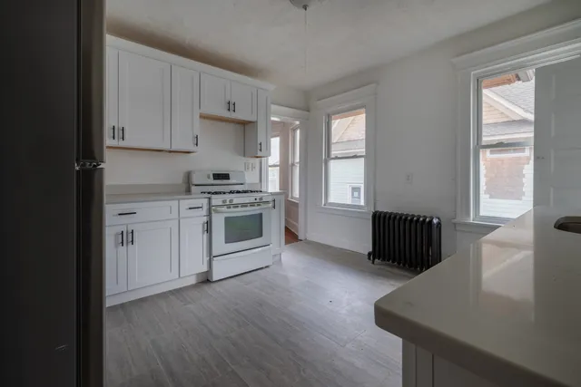 a kitchen with stainless steel appliances granite countertop a stove a sink and white cabinets