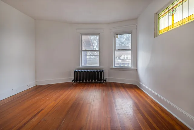 a view of an empty room with wooden floor and window