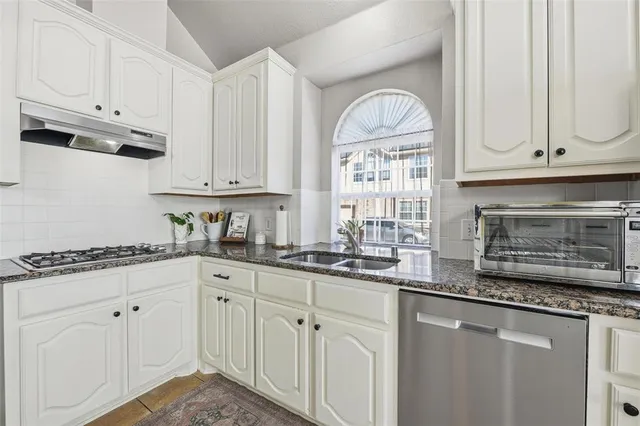 a kitchen with granite countertop white cabinets white stainless steel appliances and a sink