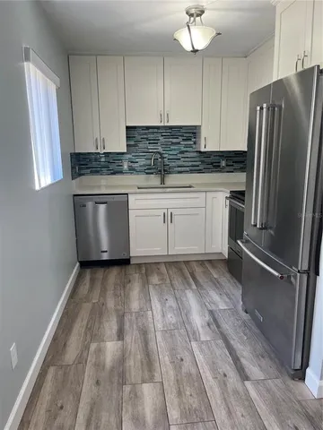 a kitchen with granite countertop a refrigerator sink and cabinets