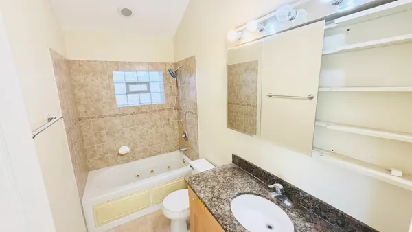a bathroom with a granite countertop toilet sink and mirror