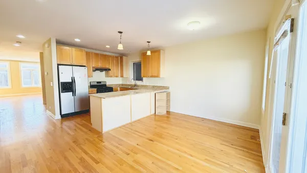 a kitchen with stainless steel appliances granite countertop a refrigerator a sink dishwasher and a stove with wooden floor