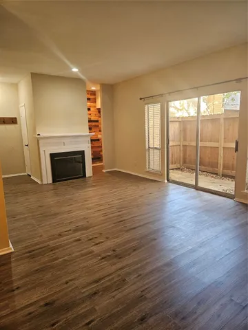 an empty room with wooden floor fireplace and windows