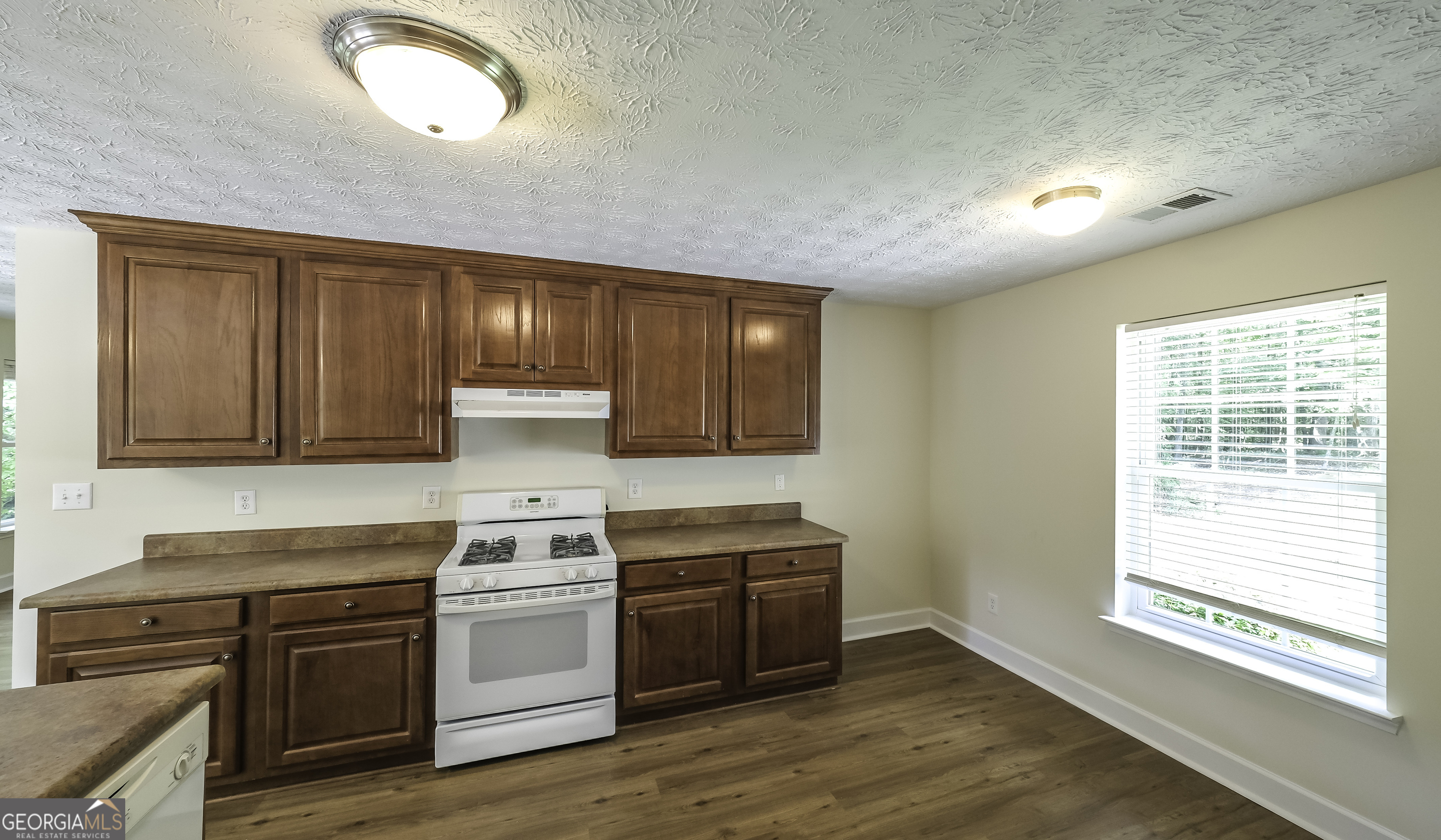 191 Tumlin Creek Road Roopville, GA 30170 - Photo 8 of 49 a kitchen with wooden cabinets and a stove top oven