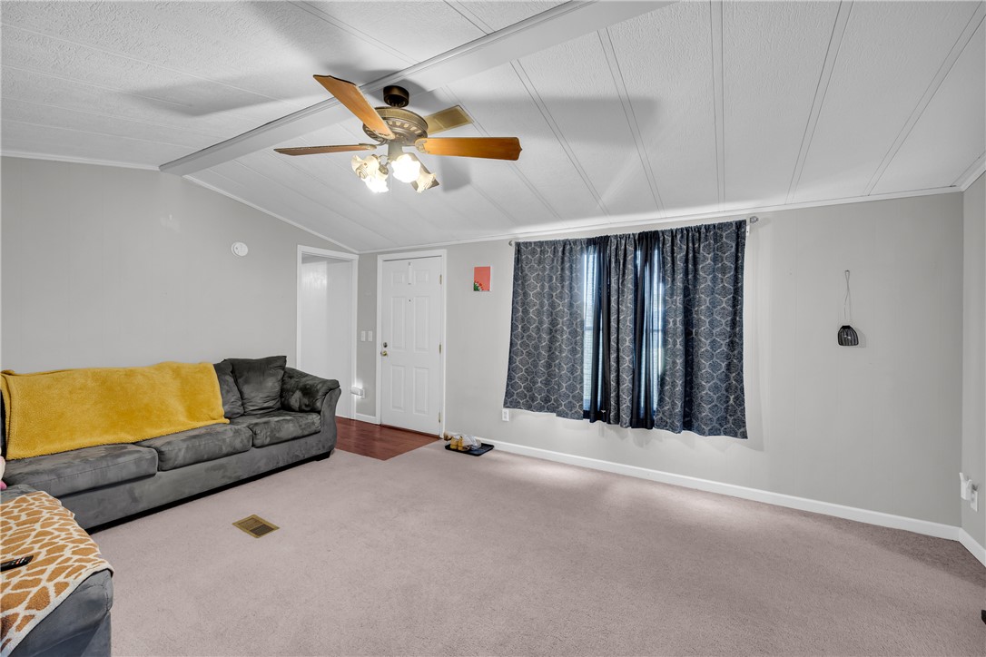 150 Newberry Road Walhalla, SC 29691 - Photo 5 of 47 A well-lit living area features a ceiling fan, plush carpeting, and direct access to another room through a classic white door.
