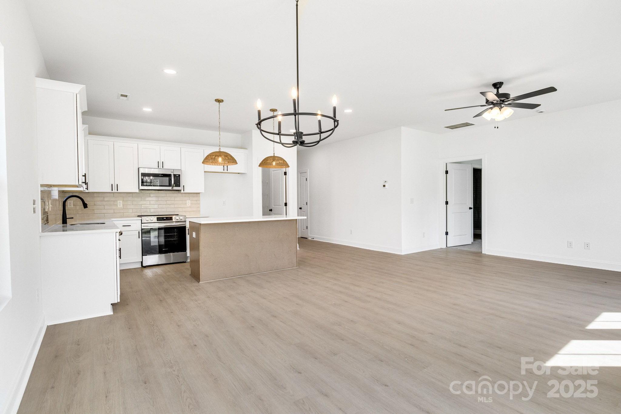 540 Church Street Locust, NC 28097 - Photo 5 of 25 a view of a kitchen with kitchen island a sink wooden floor and stainless steel appliances