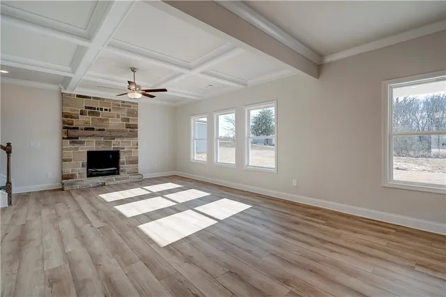 a view of an empty room with wooden floor fireplace and a window