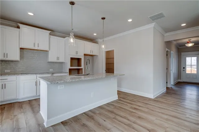 a kitchen with stainless steel appliances granite countertop a refrigerator a sink dishwasher a stove and white cabinets with wooden floor