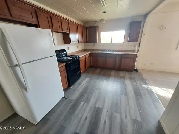 a kitchen with granite countertop a refrigerator a sink dishwasher a stove and white countertops with wooden floor