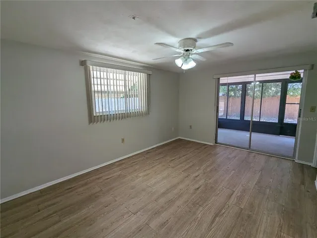 a view of an empty room with wooden floor and a window
