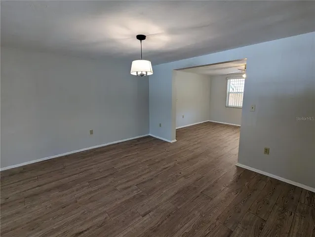 an empty room with wooden floor fan and window