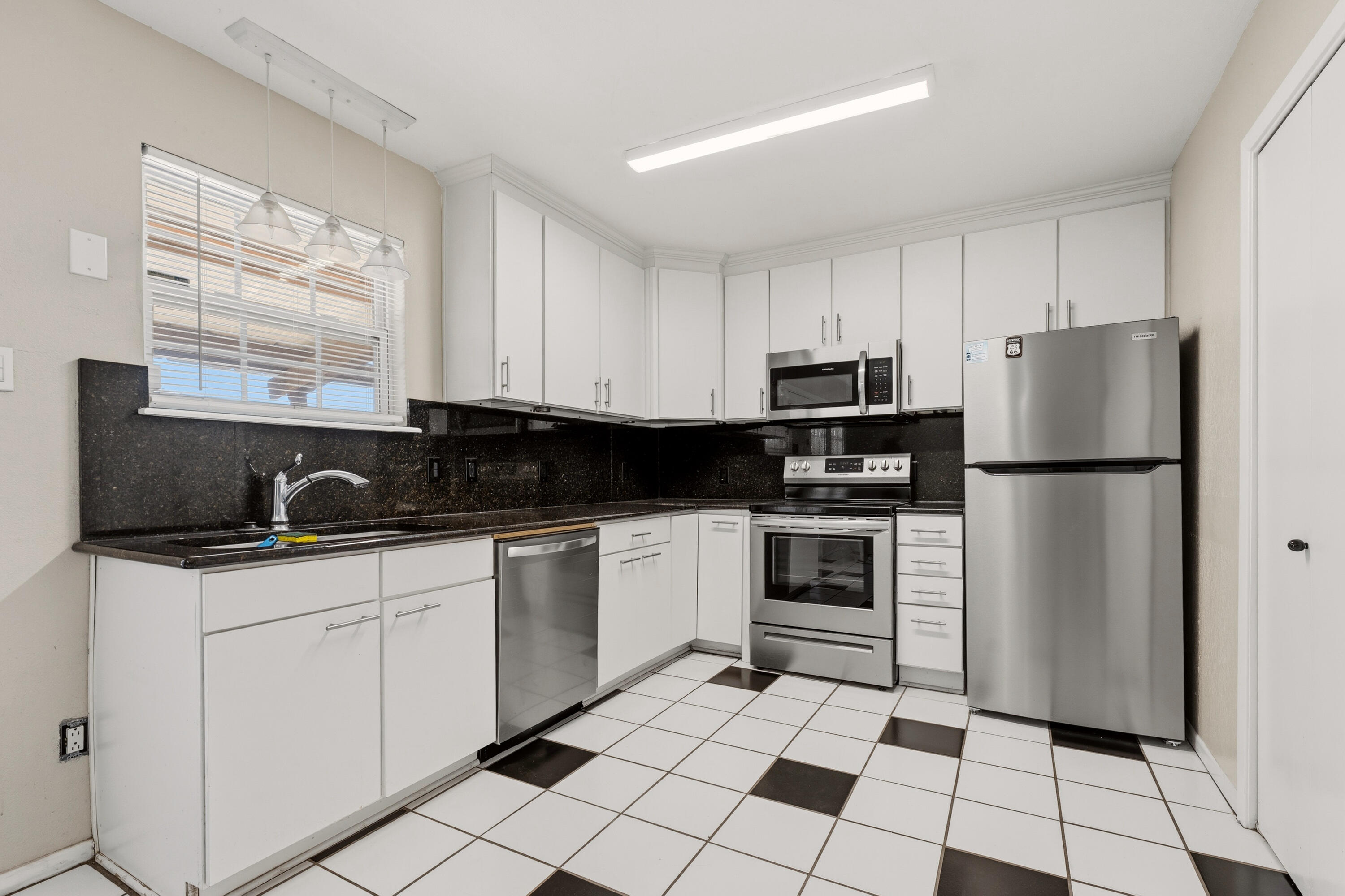 4725 48th Street Lubbock, TX 79414 - Photo 9 of 24 a kitchen with granite countertop a stove a sink and a refrigerator