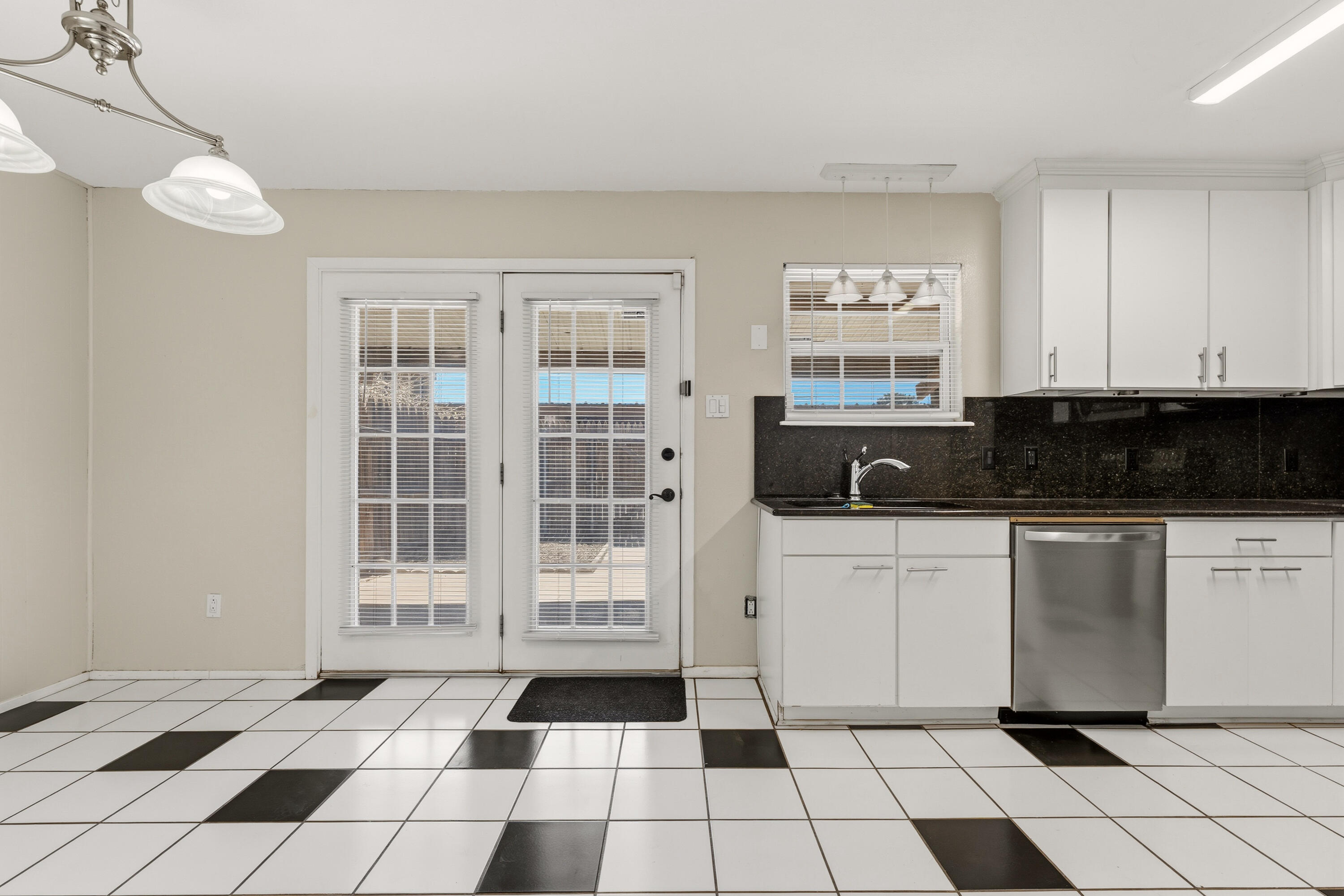 4725 48th Street Lubbock, TX 79414 - Photo 10 of 24 a kitchen with a checkered floor and white cabinets