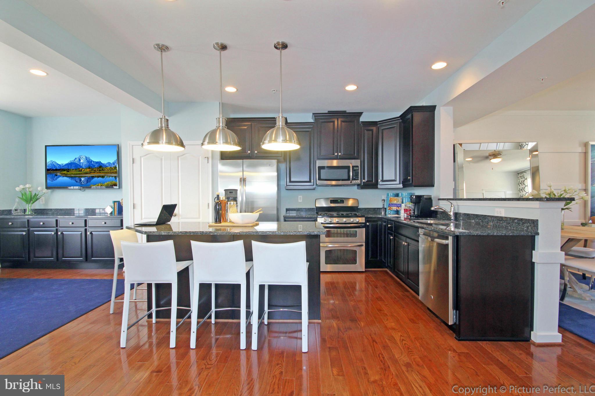 112 Mill Pond Road Frederick, MD 21701 - Photo 6 of 23 a kitchen with stainless steel appliances a dining table chairs stove and refrigerator