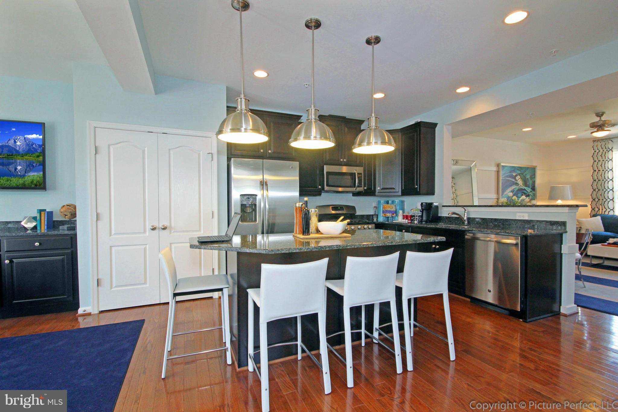 112 Mill Pond Road Frederick, MD 21701 - Photo 7 of 23 a kitchen with stainless steel appliances kitchen island granite countertop a dining table chairs and stove top oven
