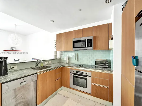 a kitchen with stainless steel appliances granite countertop a sink and a stove top oven with wooden floor
