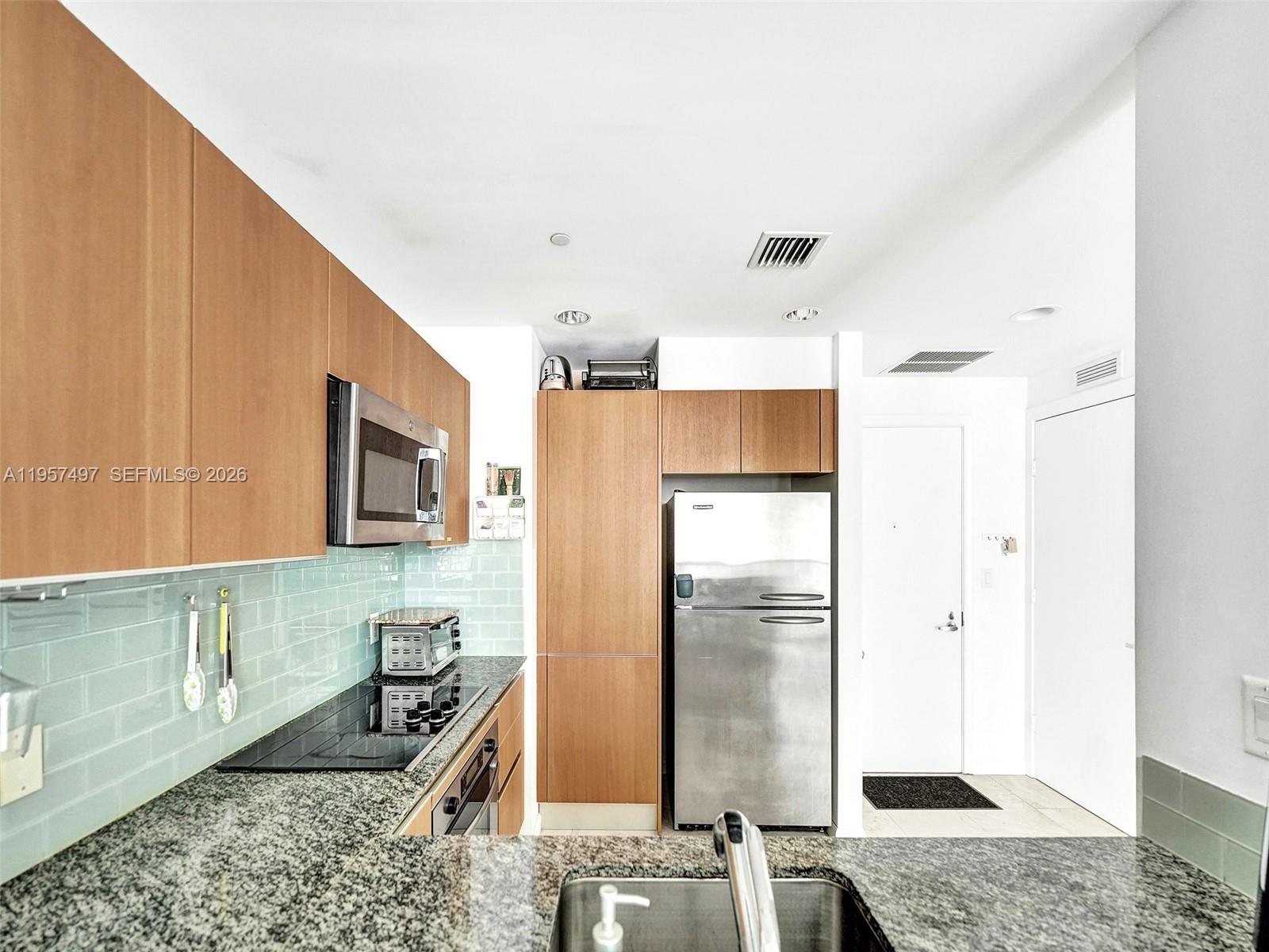 1050 Brickell Avenue, Unit 2722 Miami, FL 33131 - Photo 3 of 19 a kitchen with stainless steel appliances granite countertop a refrigerator a stove and a sink