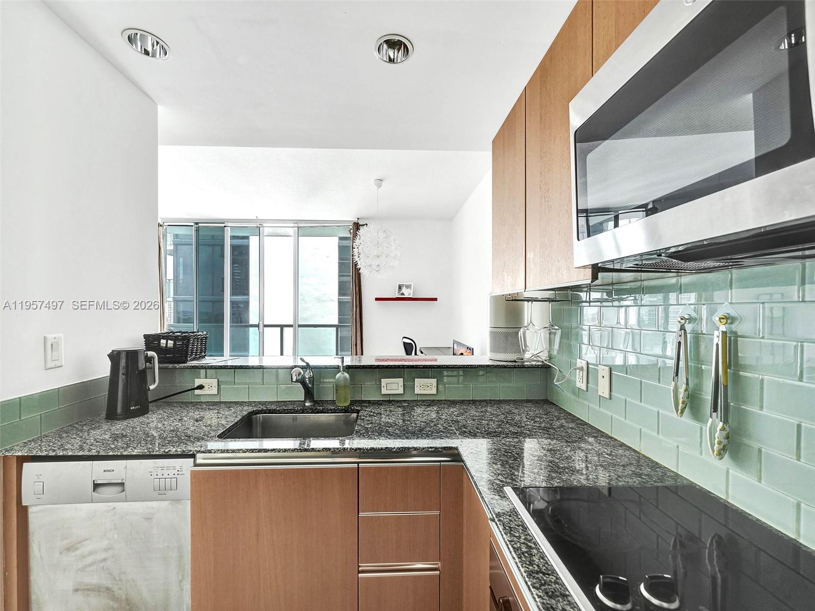 1050 Brickell Avenue, Unit 2722 Miami, FL 33131 - Photo 4 of 19 a kitchen with granite countertop a sink and a window