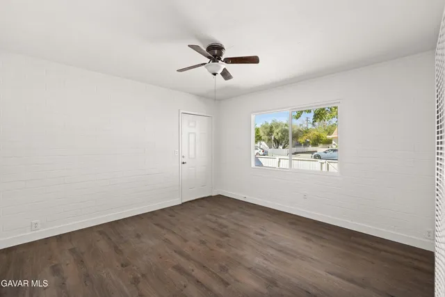 an empty room with window and ceiling fan