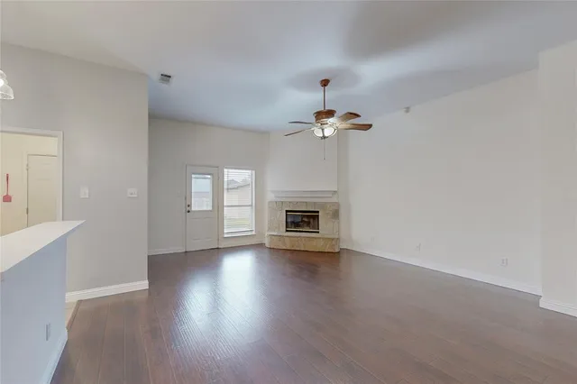 a view of an empty room with wooden floor and fireplace