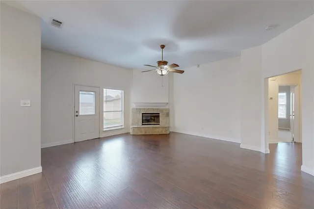 a view of an empty room with wooden floor fireplace and a window