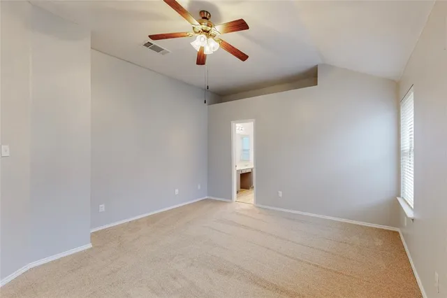 an empty room with chandelier fan and windows