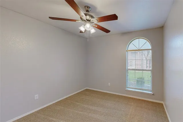 an empty room with a window and a fan
