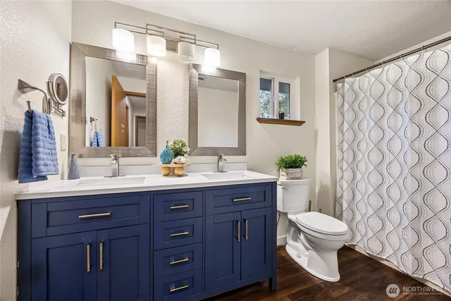 a bathroom with a double vanity sink toilet and a mirror