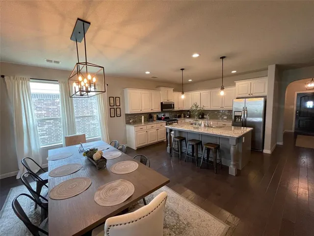a kitchen with a dining table chairs wooden floor dining table and stainless steel appliances