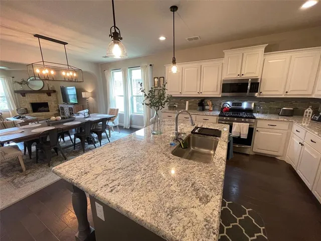 a kitchen with stainless steel appliances granite countertop a sink a stove and a wooden floors