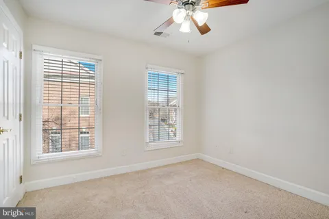 an empty room with windows and chandelier fan