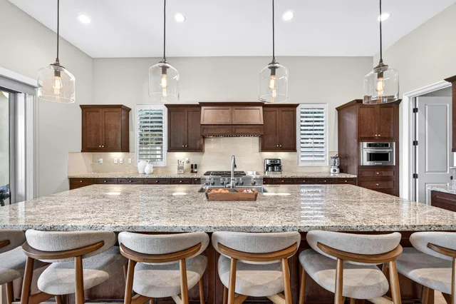 a kitchen with kitchen island granite countertop wooden cabinets and a refrigerator