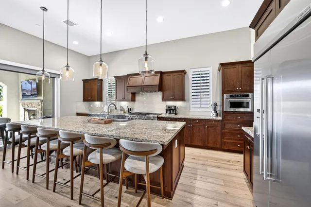 a kitchen with kitchen island granite countertop a table chairs microwave and refrigerator