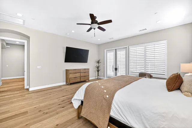 a spacious bedroom with a bed and a flat screen tv