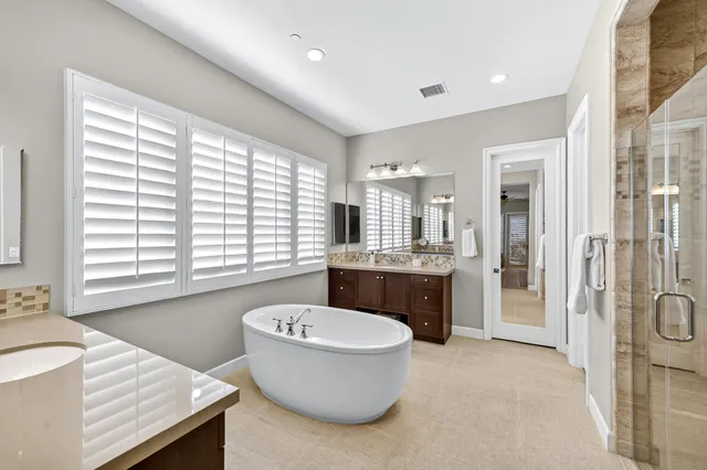a bathroom with a granite countertop sink and mirror with bathtub