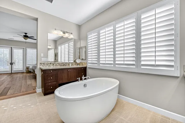 a bathroom with a bathtub a sink a mirror and a window