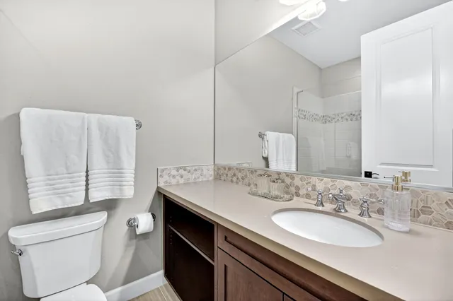 a bathroom with a granite countertop sink toilet and mirror