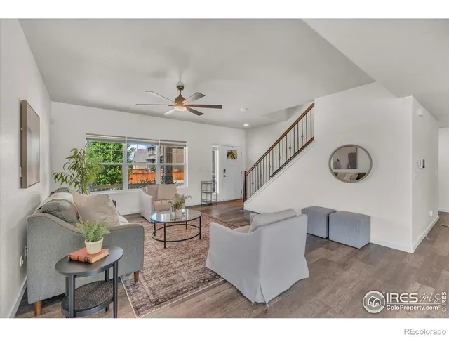 a living room with couches and kitchen view with wooden floor